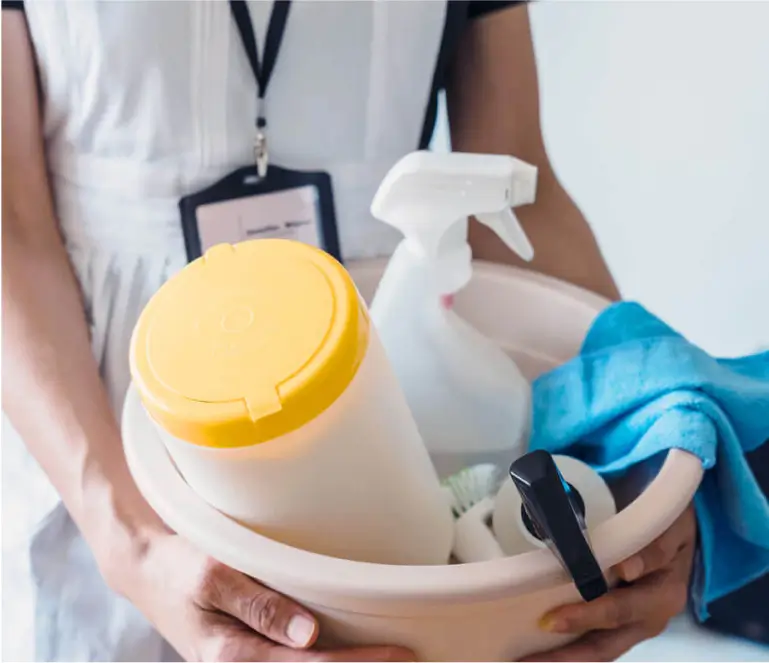 A person holding a bucket of cleaning products