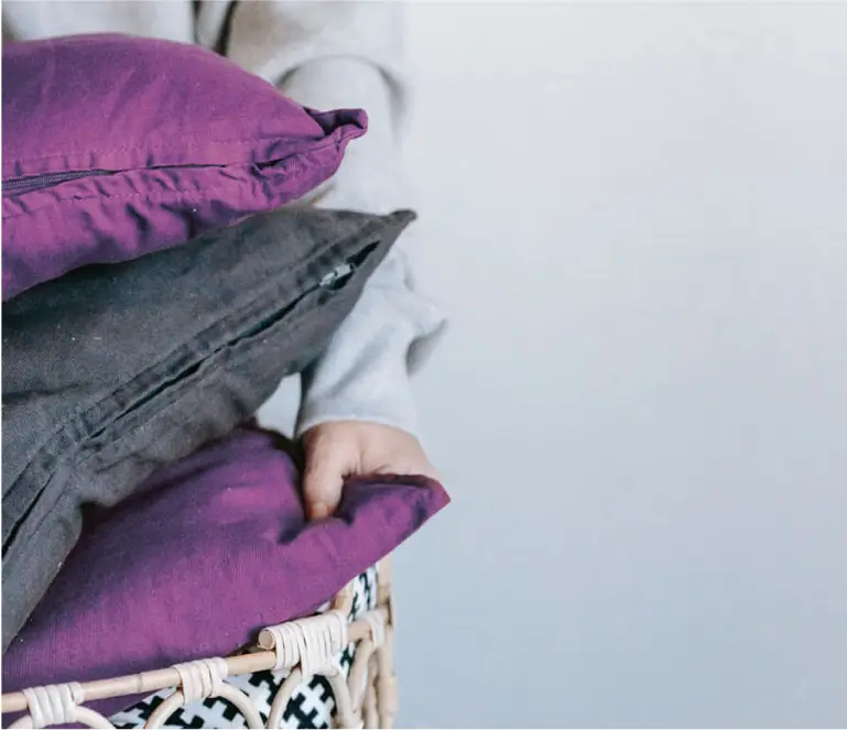 A person holding a basket of pillows and blankets